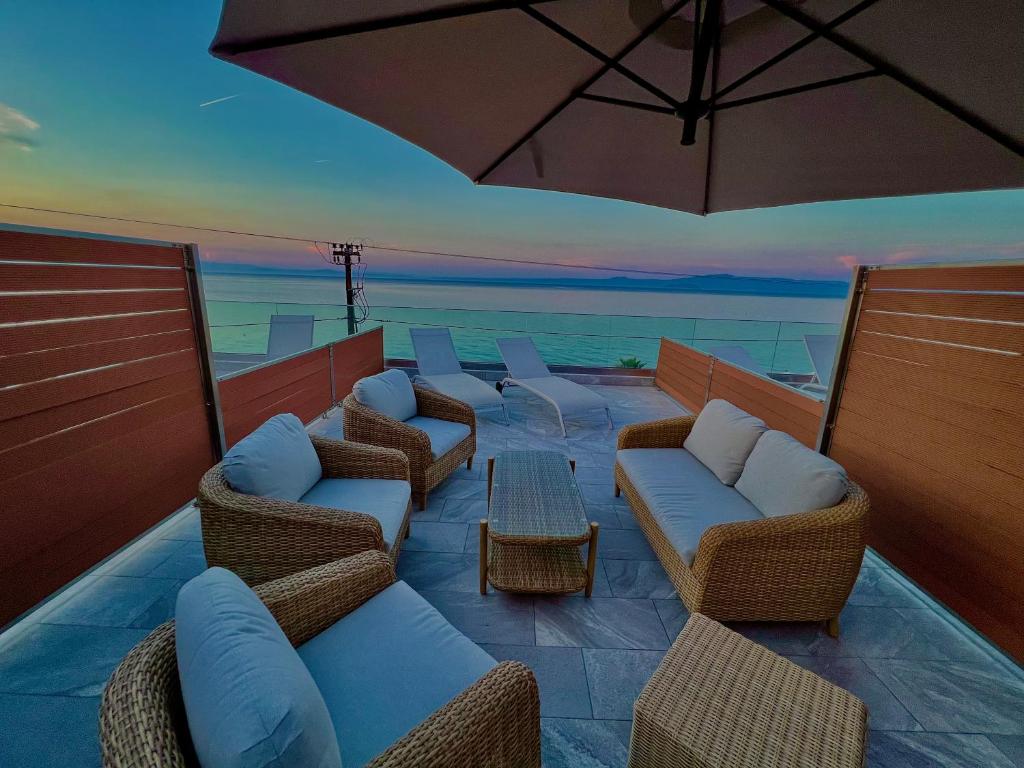 a patio with chairs and tables and an umbrella at Hotel Pefkohori Beach in Pefkochori