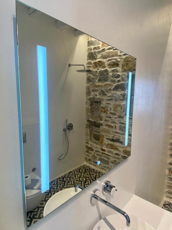 a bathroom mirror with a sink and a stone shower at Thomas Villas on the beach Katapola in Katapola