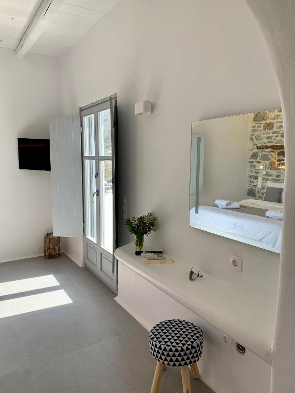 a white room with a bed and a mirror at Thomas Villas on the beach Katapola in Katapola