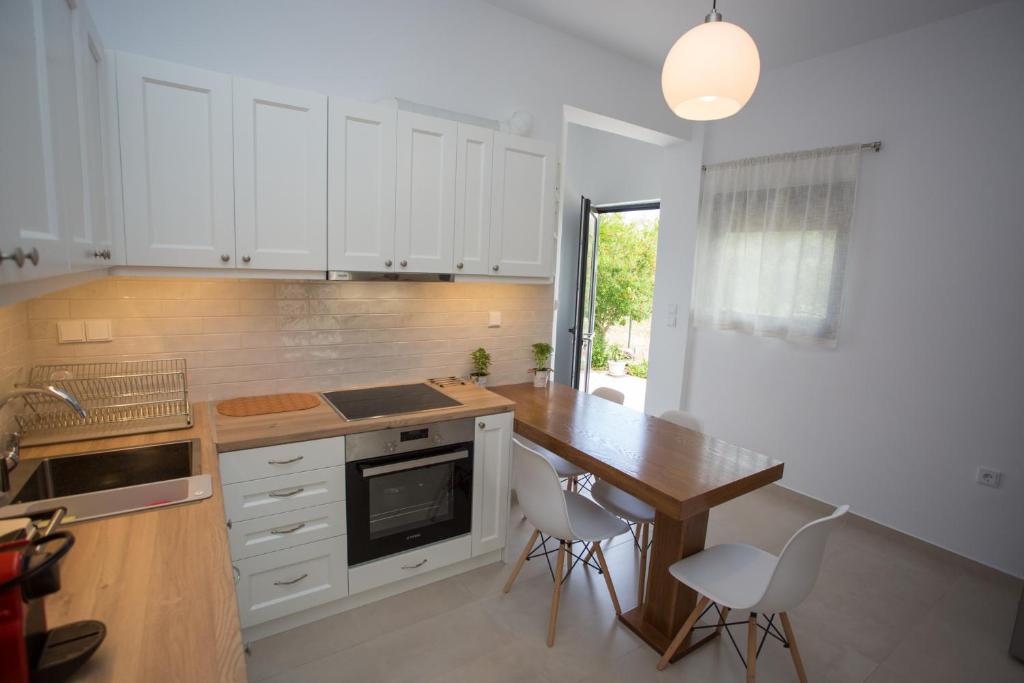 une cuisine avec une table en bois et des armoires blanches dans l'établissement George‘s Place Kastrosikia, à Kastrosikia