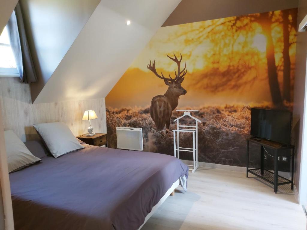 a bedroom with a painting of a deer on the wall at le bonheur des plumes in Montmartin-en-Graignes