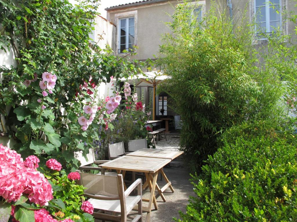 a garden with a wooden table and some flowers at Hôtel Le Sénéchal in Ars-en-Ré