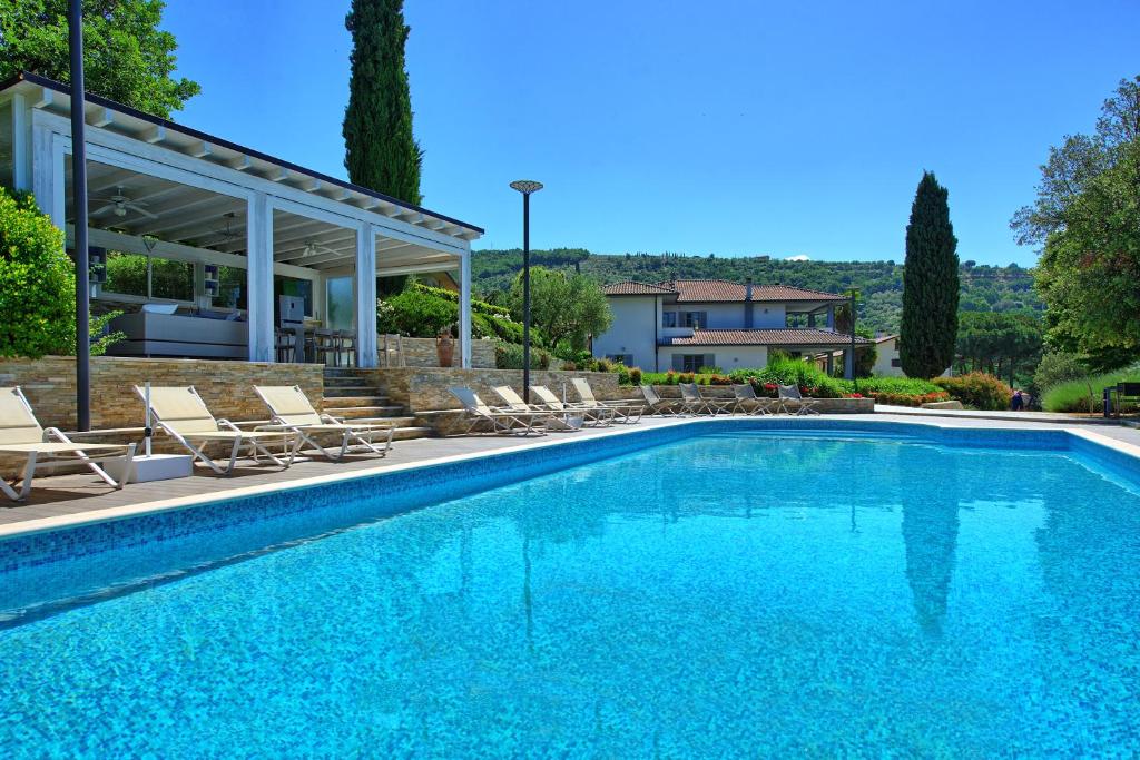 a swimming pool with chairs and a house at Casa White by PosarelliVillas in Castiglion Fiorentino