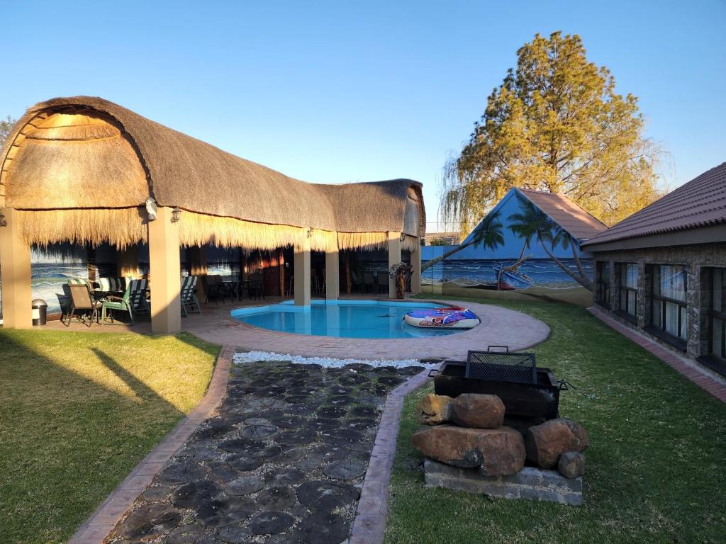 a pavilion with a swimming pool in a yard at The Log Cabin Apartments Hotel in Standerton