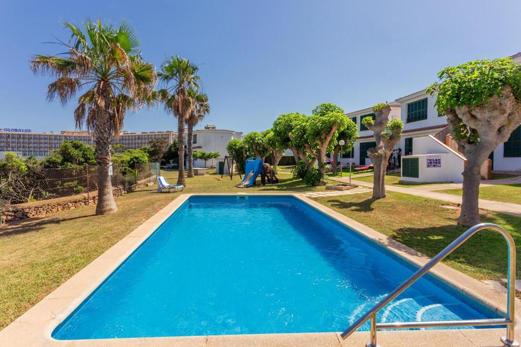 a swimming pool in front of a house with palm trees at Villa Elfa in Cala en Forcat