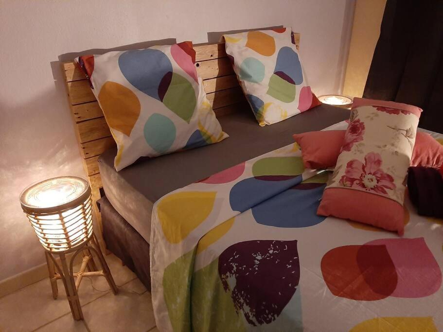 a bedroom with a bed with colorful sheets and pillows at Studio Perle de Zanzibar Trois-Ilets in Les Trois-Îlets