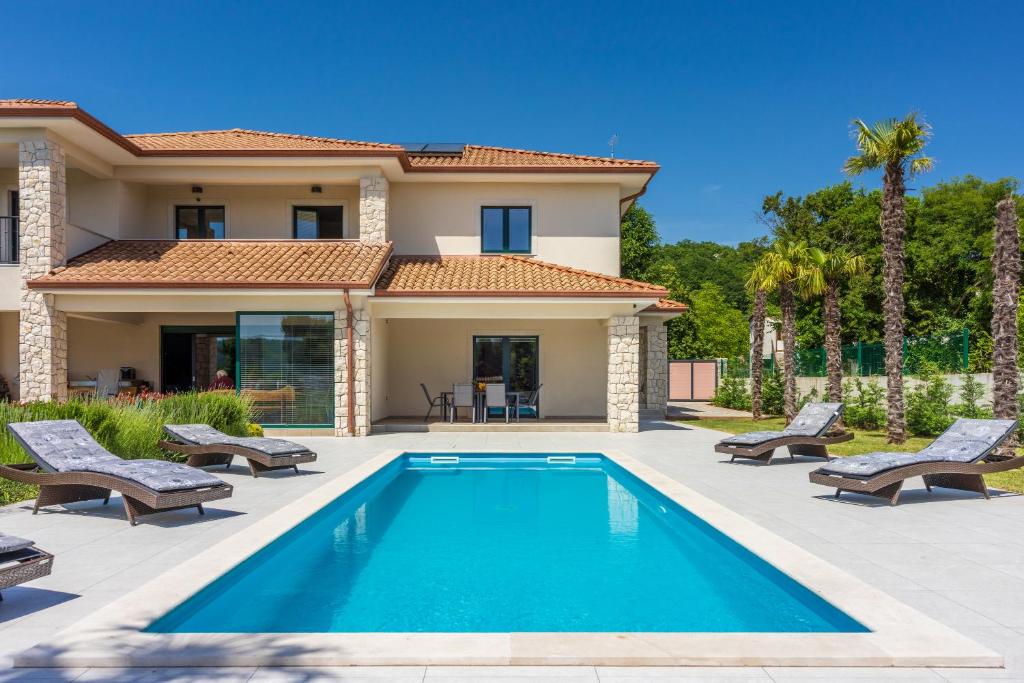 a villa with a swimming pool in front of a house at Villa Palma with Heated Private Pool in Podhum