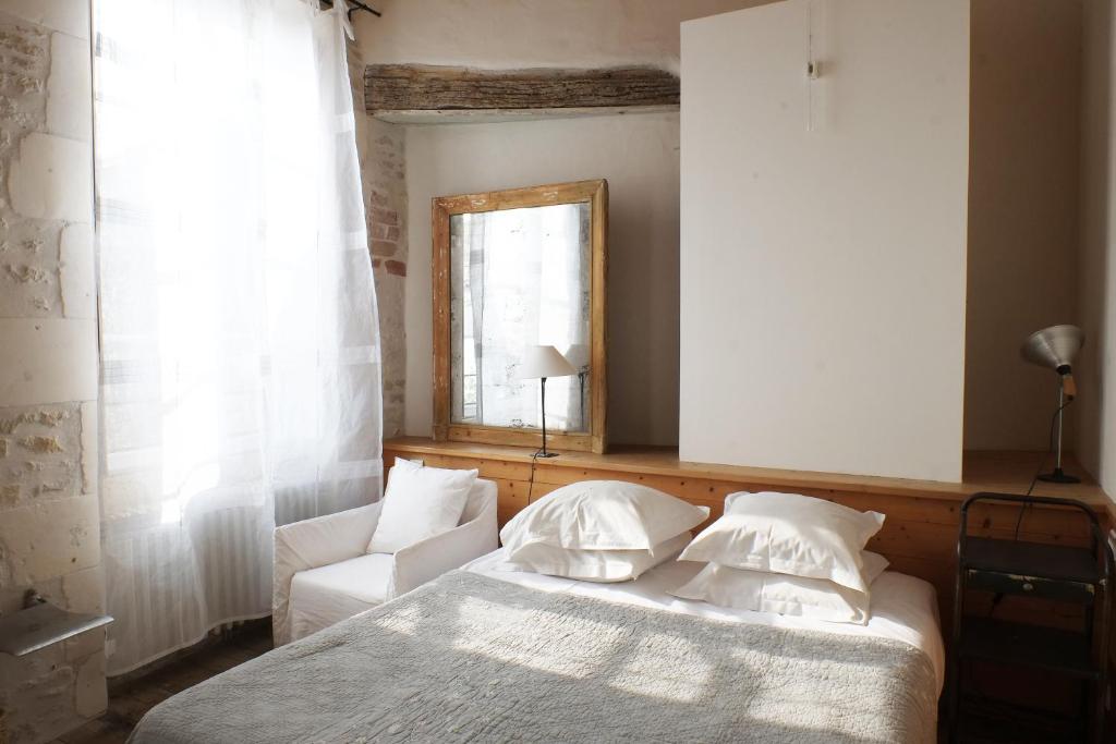 a bedroom with a bed and a chair and a mirror at Hôtel Le Sénéchal in Ars-en-Ré