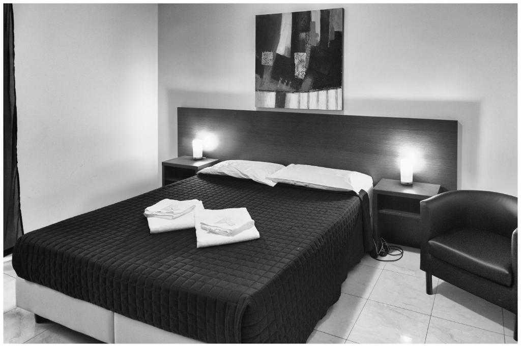 a black and white bedroom with a bed and a chair at Hostel Mosaic in Rome