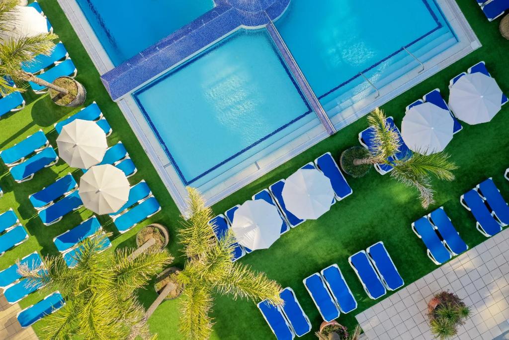 an overhead view of the pool at a resort with palm trees at htop Platja Park #htopFun in Platja d'Aro