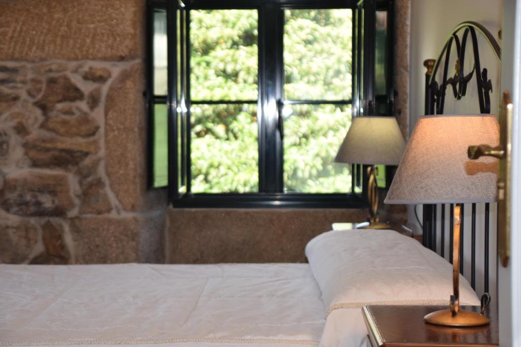 a bedroom with a bed with two lamps and a window at Casa Videira - Hotel rural cerca del mar in Bueu