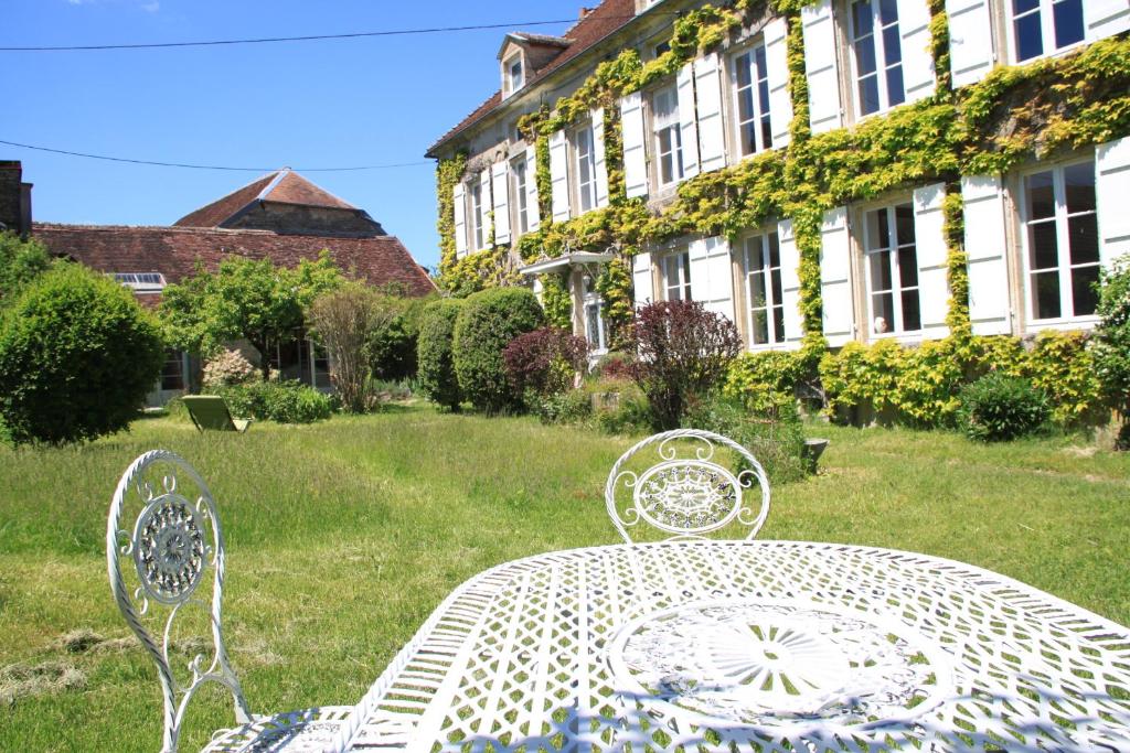 une table et des chaises blanches dans une cour avec un bâtiment dans l'établissement Maravillon - Chambres d'hôtes, à Villon