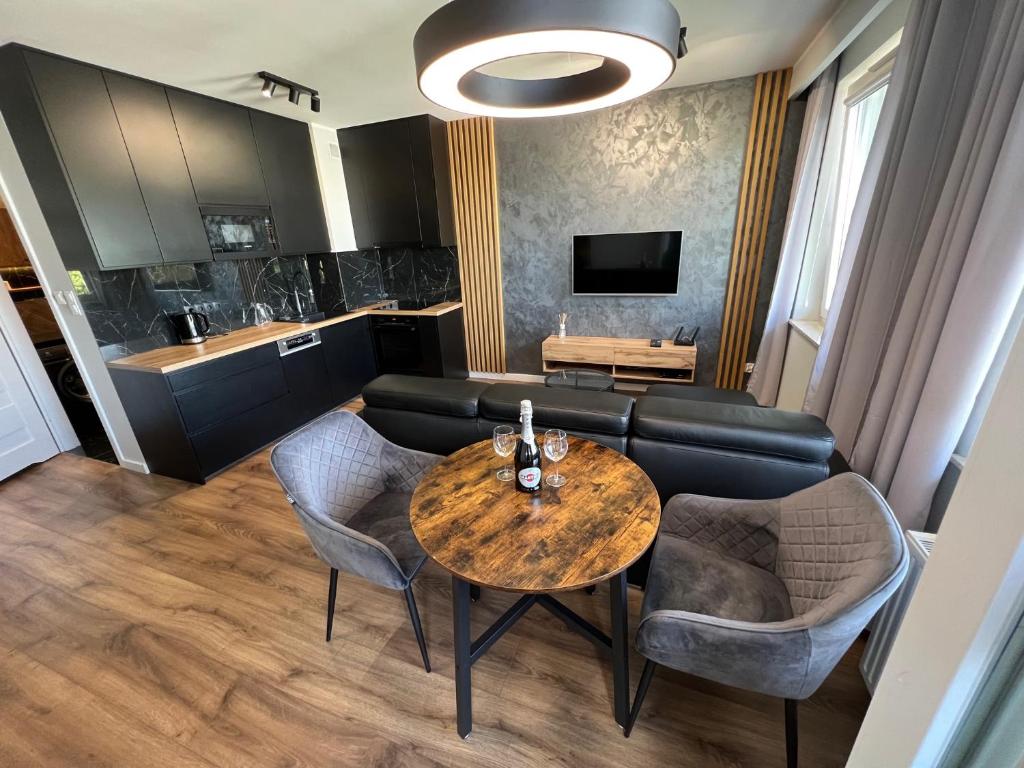 Tricity Apartments - Wilga Park في غدانسك: غرفة معيشة مع أريكة وطاولة وكراسي