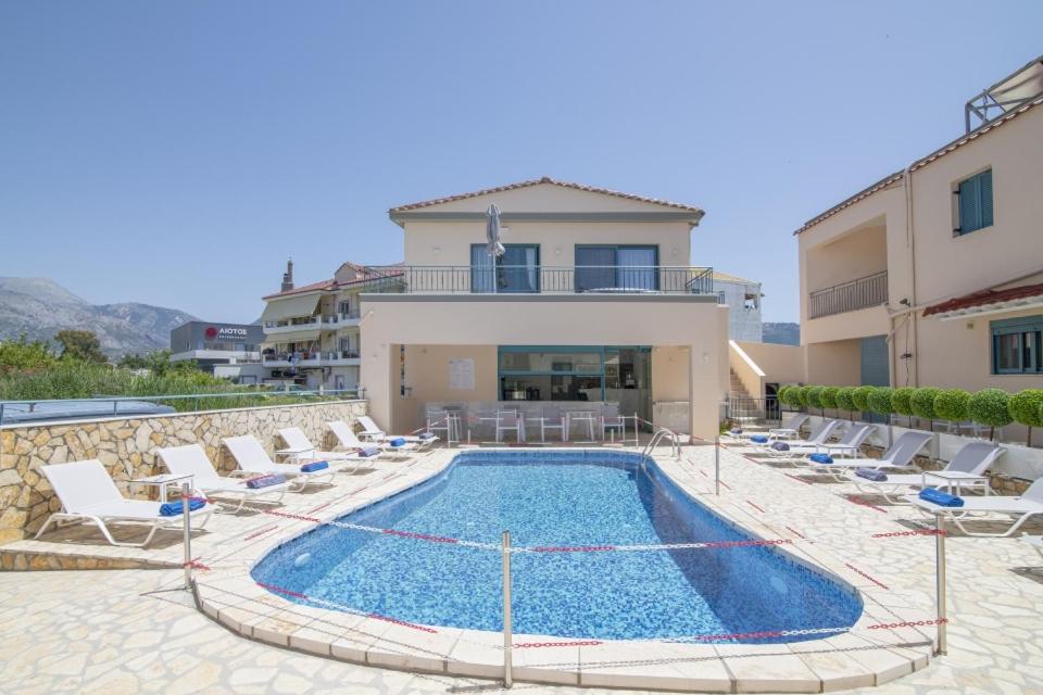 a swimming pool with chairs and a house at Anemos Villas in Mitika