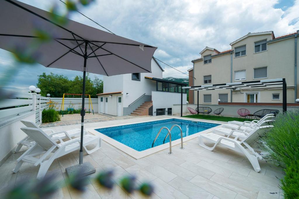 una piscina con 2 sillas y una sombrilla en Luxury with gallery, heated pool only for you-KLIS CRO, en Klis