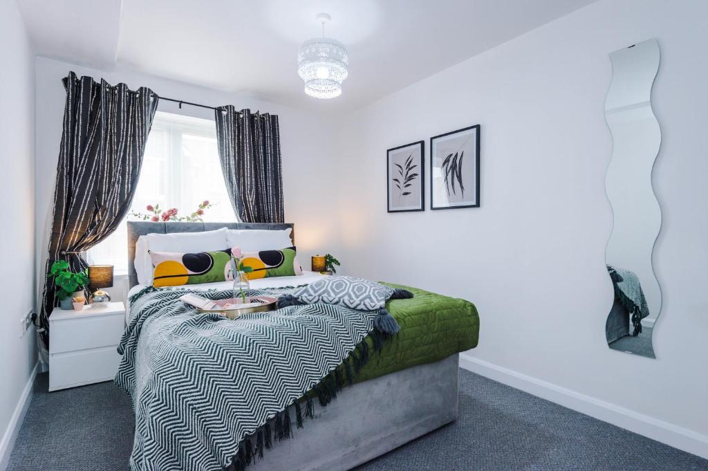 a bedroom with a bed with a green and white comforter at Carterson Serviced Apartment Coventry in Coventry