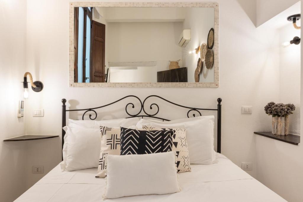a bedroom with a bed with white pillows and a mirror at Cagliarifornia in Cagliari