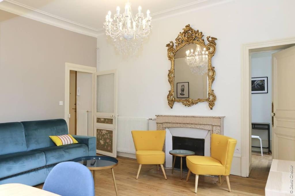 een woonkamer met een blauwe bank en gele stoelen bij La Chouette in Dijon