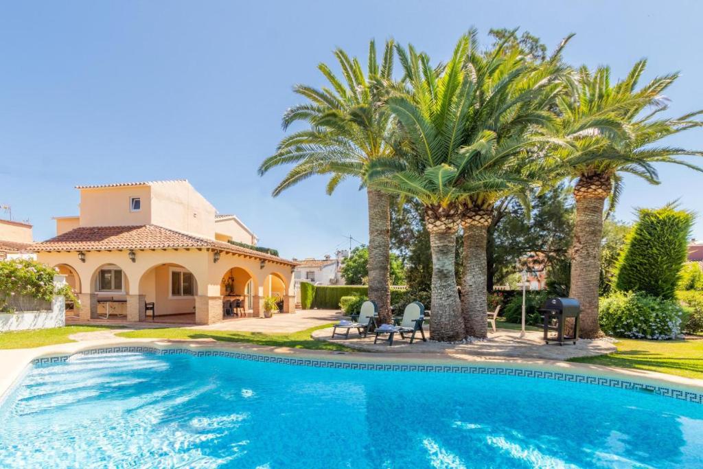 een zwembad met palmbomen voor een huis bij Casa Segaria in Denia