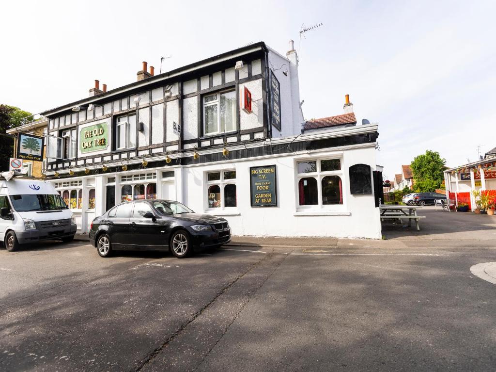 a black car parked in front of a white building at Old Oak Tree Inn in Hounslow