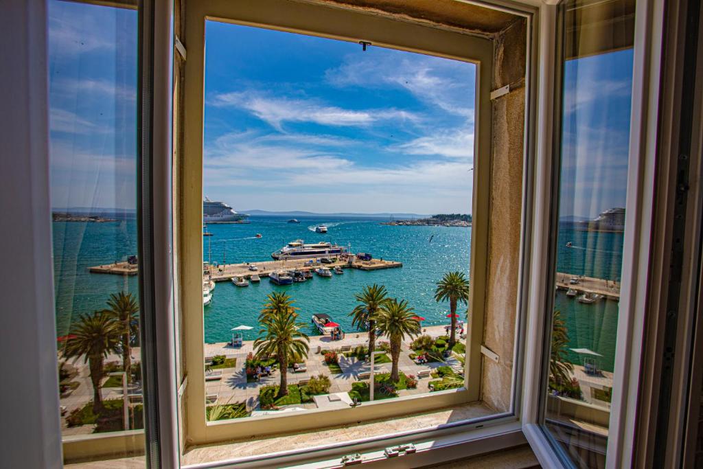 a window with a view of a beach and the ocean at Riva - the heart of palace in Split