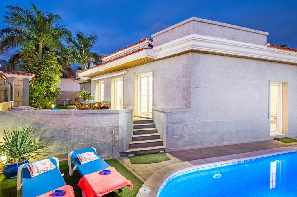 a house with a swimming pool and two chairs at villa leonardo in Puerto de Santiago