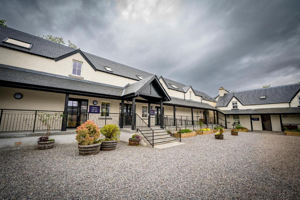 une rangée de bâtiments avec des escaliers et des plantes en pot dans l'établissement Loch Ness Bunk Inn, à Drumnadrochit