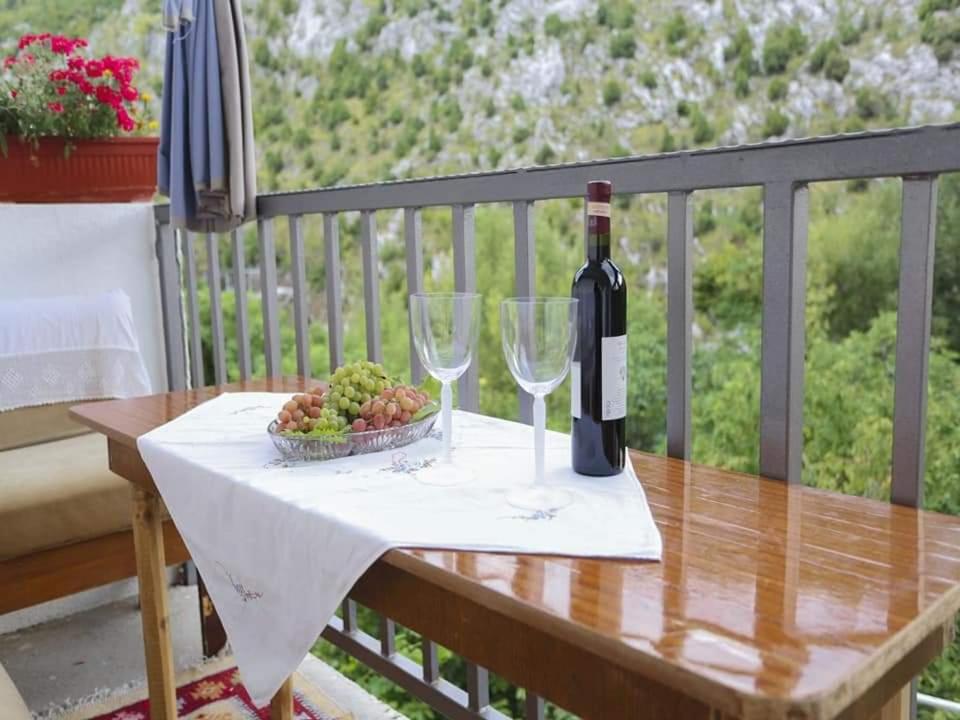 a table with two wine glasses and a bowl of grapes at Apartman Maida in Blagaj