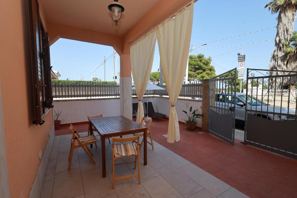 Un patio con una mesa y sillas en un balcón. en Golden Beach Home Holiday, en Avola