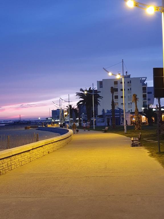 a walkway next to the beach at night at Appartement privé dans maison individuelle in Le Grau-du-Roi