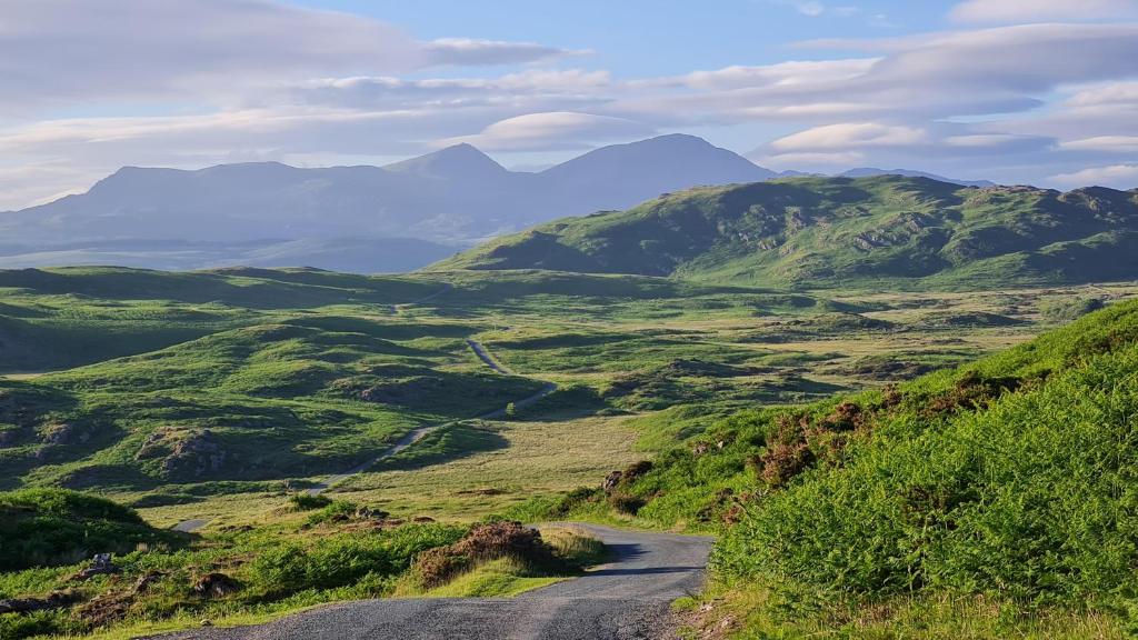 a winding road on a hill with mountains in the background at Mountain View in Ulverston