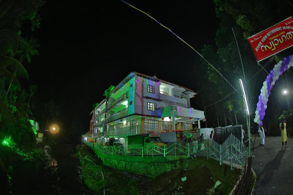 a building with green and purple at night at Thodupuzha 4-bhk Luxury Home awy from home in Thodupuzha