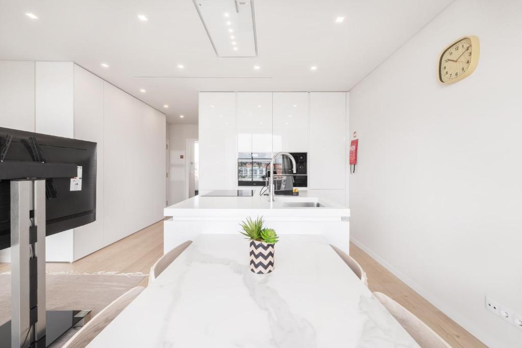 a white kitchen with a potted plant on a table at Ocean Apartment by Olala Homes in Cascais