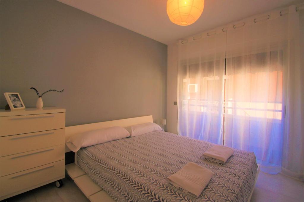 una camera da letto con un letto, un comò e una finestra di Apartamento CasaTuris con vistas a la playa del Postiguet A103 ad Alicante