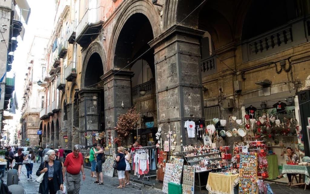 un grupo de personas caminando por un mercado frente a un edificio en Hotel B&B Spaccanapoli, en Nápoles