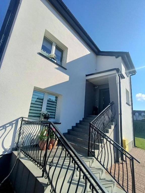 a white house with stairs and a balcony at Pokoje u Bożeny in Ostrowo
