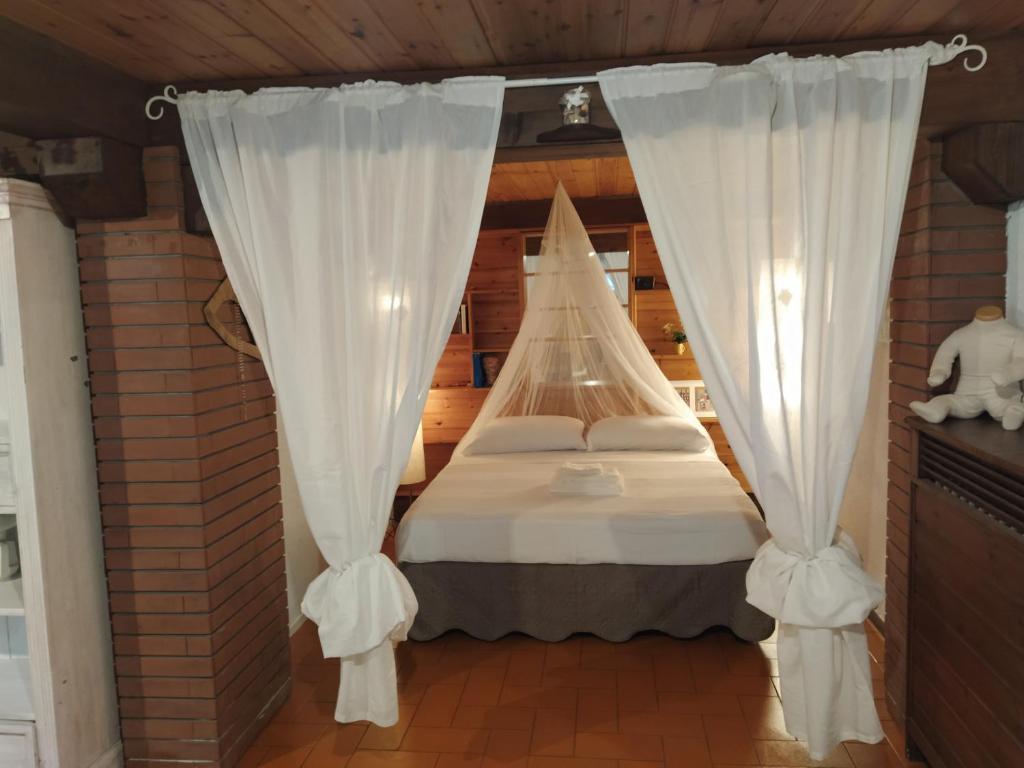 1 dormitorio con 1 cama con cortinas blancas en Al civico 2 Apartment, en Rávena