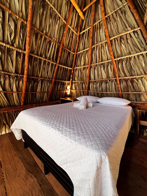 a bedroom with a bed in a thatched room at Macarena Paredon in El Paredón Buena Vista