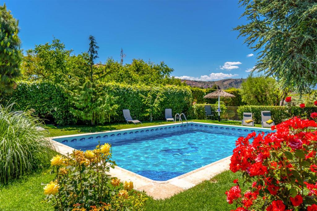uma piscina num quintal com flores em Lujosa Casa Rural el Altico con barbacoa, chimenea y zona infantil em Cehegín