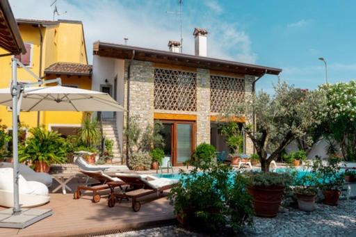 a house with a patio with chairs and an umbrella at B&B Borgo Margherita in Udine
