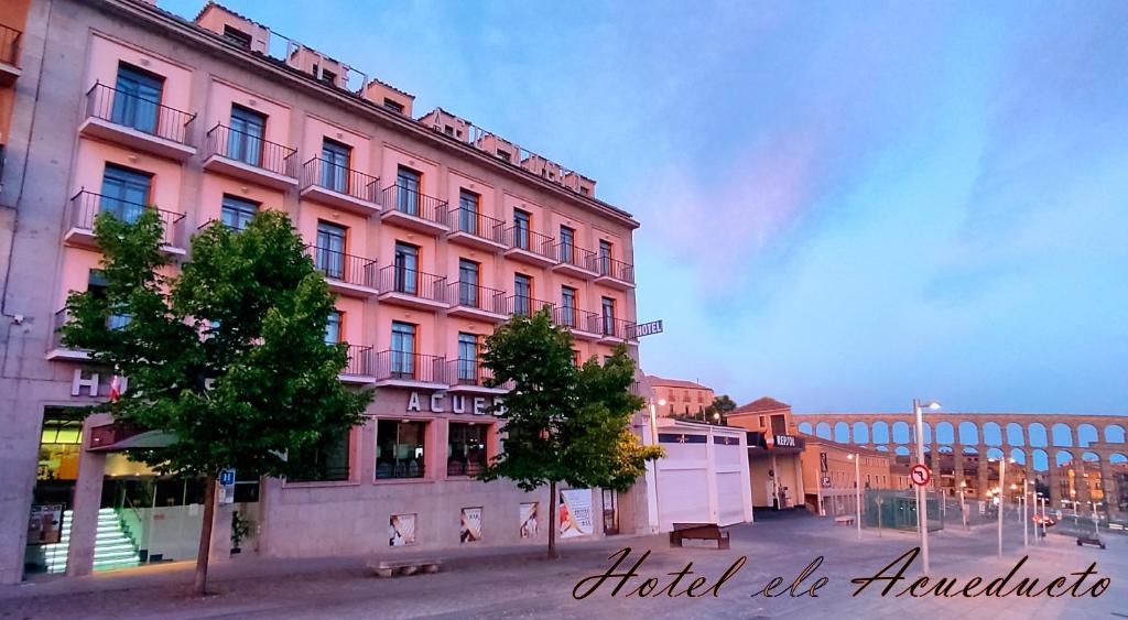 ein rosafarbenes Gebäude an der Straßenseite in der Unterkunft Hotel ELE Acueducto in Segovia