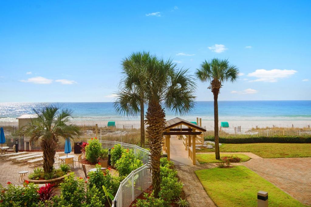 a view of a garden with palm trees and the beach at Sterling Sands 111 in Destin
