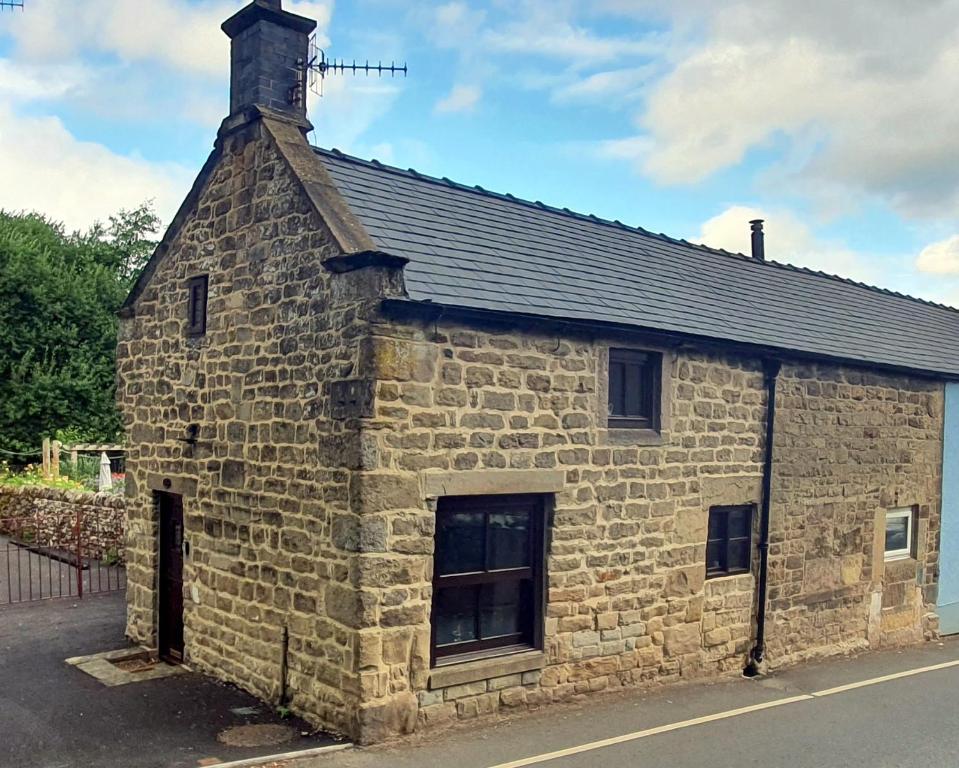 an old stone building with a roof at Stanton Cottage, Youlgrave Nr Bakewell in Bakewell