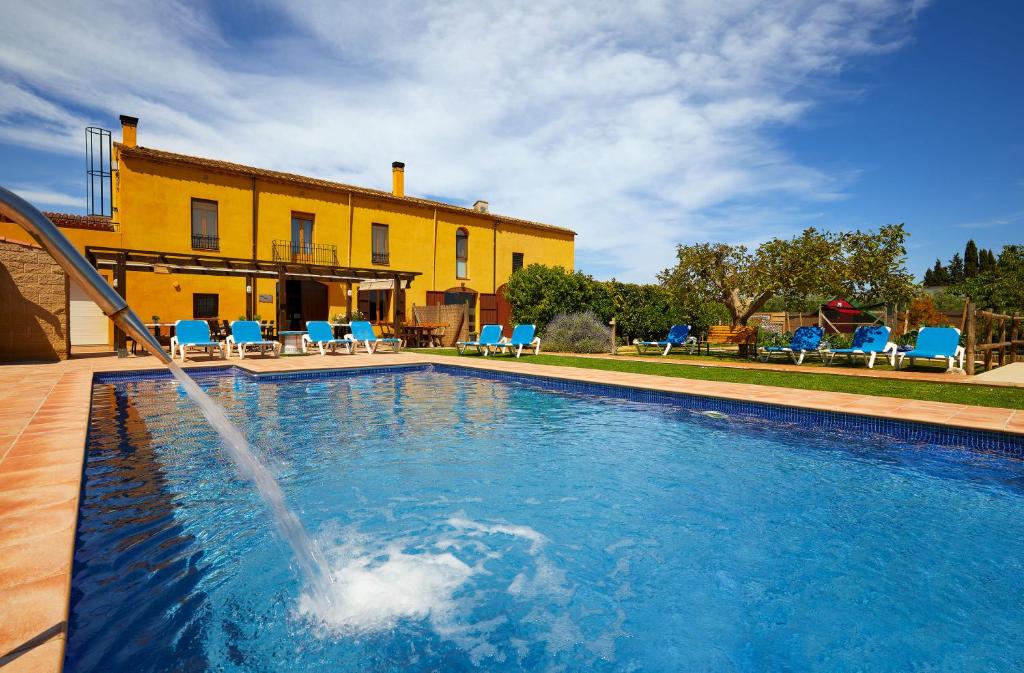 une piscine avec toboggan en face d'une maison dans l'établissement Mas Ribas Turismo Rural, à Montiró
