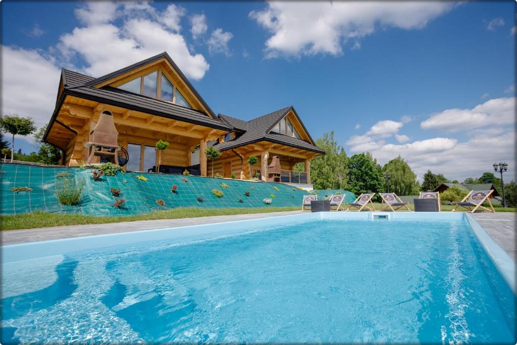 a house with a swimming pool in front of a house at Zdrojowy Gościniec - domki Rabka-Zdrój in Rabka-Zdrój