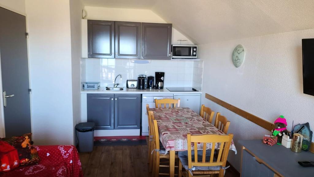 une cuisine avec une table et des chaises dans une pièce dans l'établissement Appartement cosy à Valmeinier avec vue montagne et piscine, à Valmeinier
