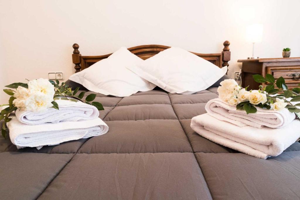 Una cama con toallas y flores encima. en COBEXO2 Moderno y tranquilo en Sabiñánigo, en Sabiñánigo