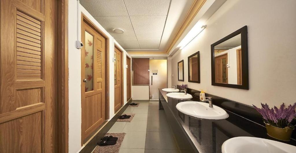 een badkamer met drie wastafels en een rij spiegels bij Alleyway Hostel in Ho Chi Minh-stad