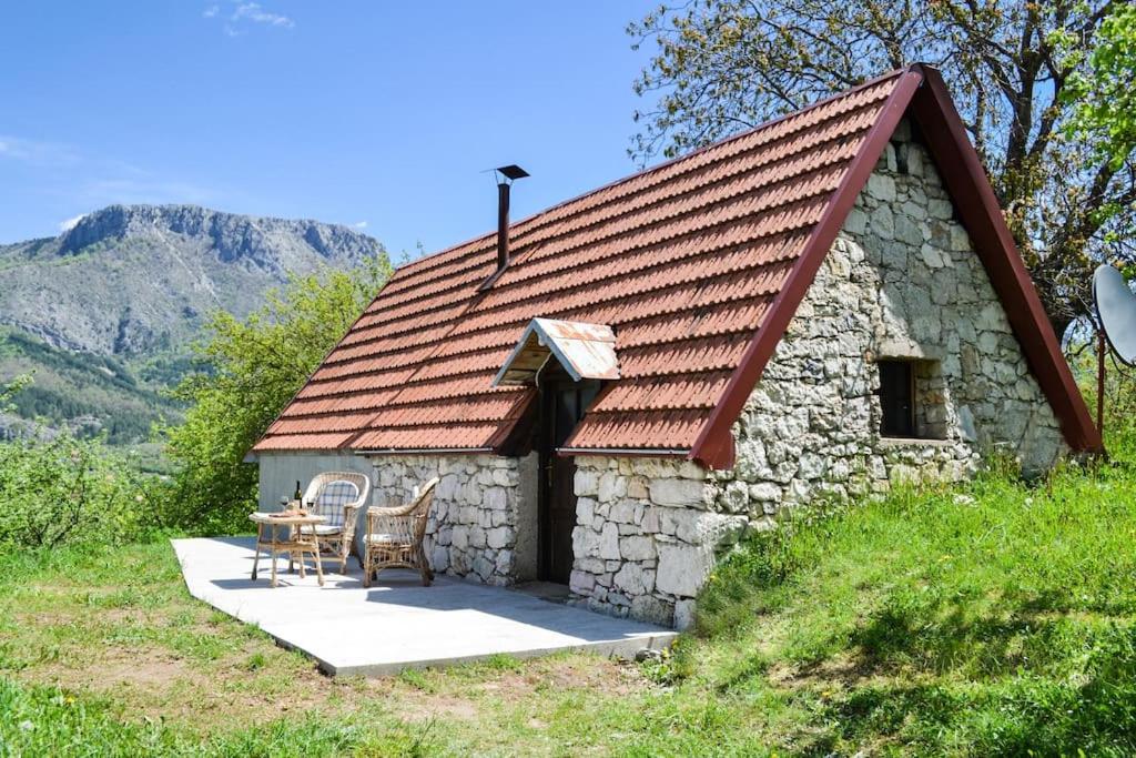 a small stone house with a red roof and a table at Grandma's Hut in Nikšić