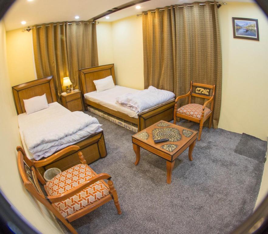 a room with two beds and a table and chairs at Ringchan Guest House & Restaurant in Skardu